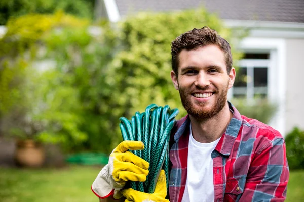 Uomo che trasporta tubo da giardino in cortile — Foto Stock