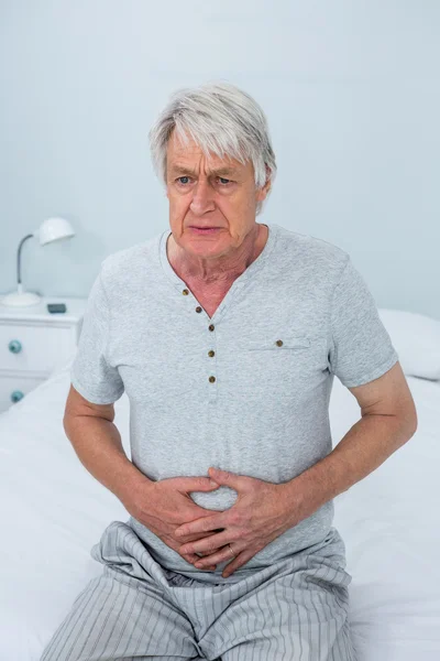 Senior man aan te raken van maag — Stockfoto