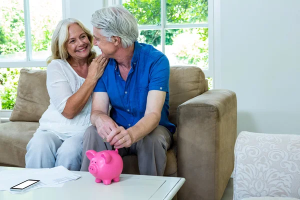 Ehepaar steckt Münze in Sparschwein — Stockfoto