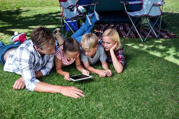 Сім'я лежить на траві і використовує планшет — стокове фото