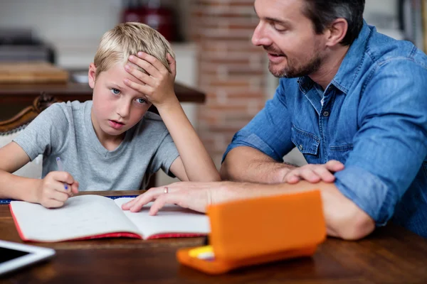Father helping son with homework in kitchen — Stock Photo, Image