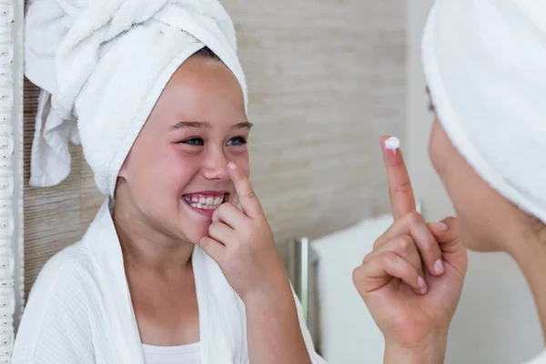 Mother and daughter applying moisturizer on nose — Stock Photo, Image