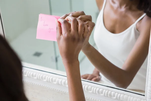 Mulher colando nota no espelho — Fotografia de Stock