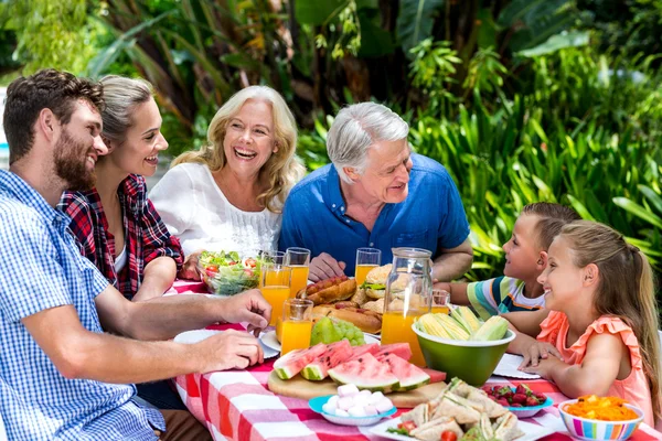Familia teniendo comida en la mesa en el patio — Foto de Stock