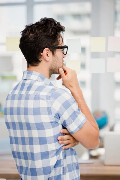 Hombre reflexivo mirando notas pegajosas — Foto de Stock