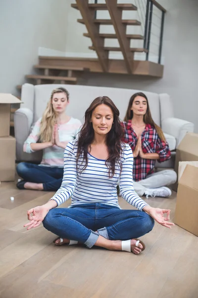 Amici che eseguono yoga in una nuova casa — Foto Stock