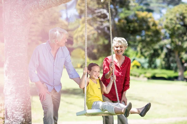 Abuelos empujando nieta en swing — Foto de Stock