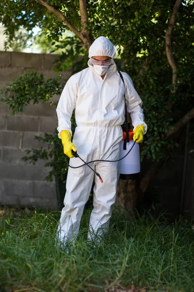 Homem pulverizando pesticida na grama — Fotografia de Stock