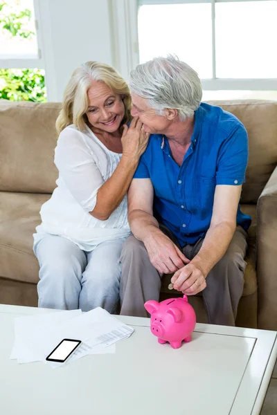 Ehepaar steckt Münze in Sparschwein — Stockfoto