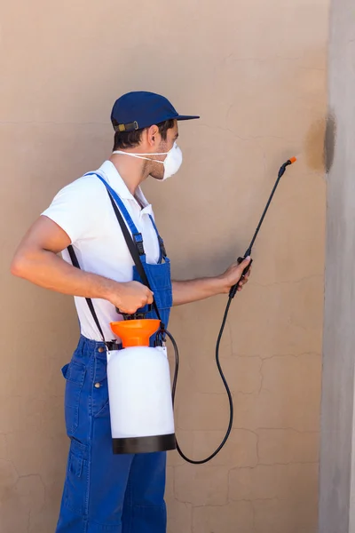 Homem pulverizando pesticida na parede — Fotografia de Stock