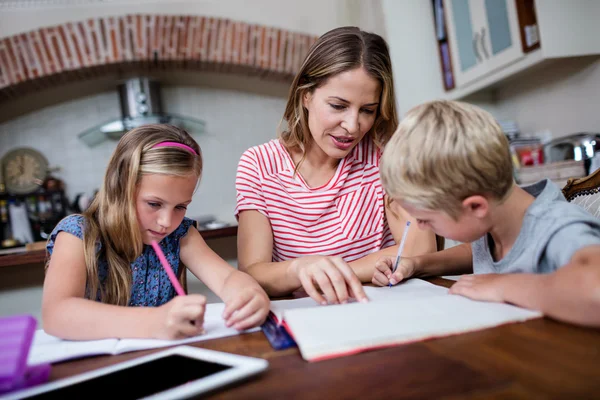 Mère aidant les enfants avec leurs devoirs — Photo