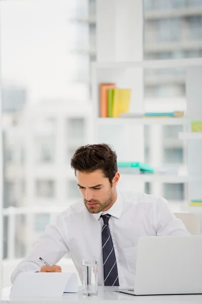 Empresario usando laptop y tomando notas — Foto de Stock