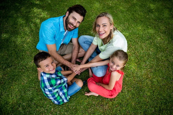 Família amontoando as mãos enquanto sentado na grama — Fotografia de Stock
