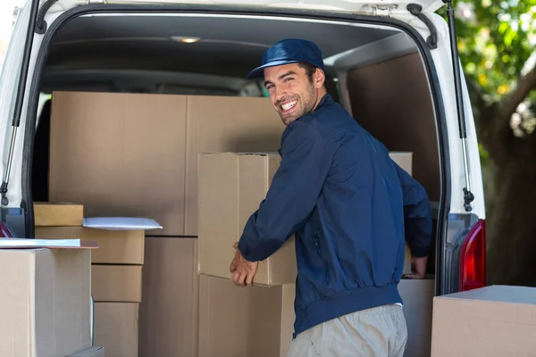 Delivery man loading cardboard box in van Stock Image