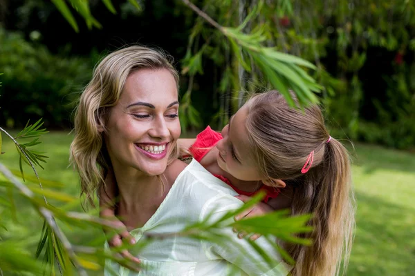 Mãe piggybacking filha no quintal — Fotografia de Stock