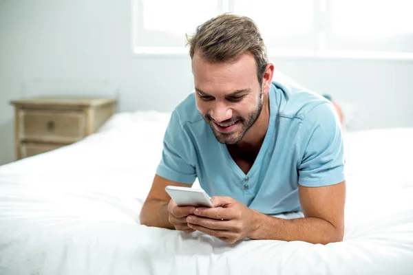 Man using cellphone on bed — Stock Photo, Image