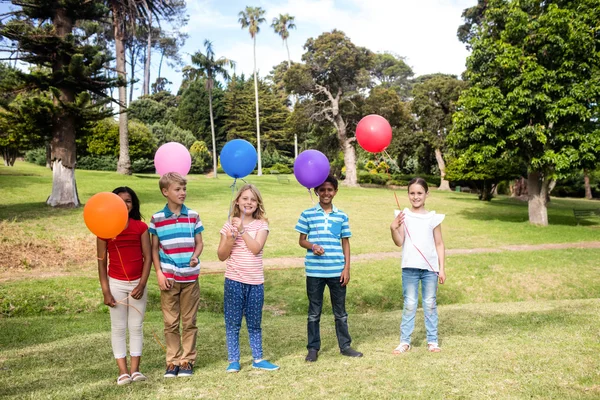 Crianças de pé com balões no parque — Fotografia de Stock