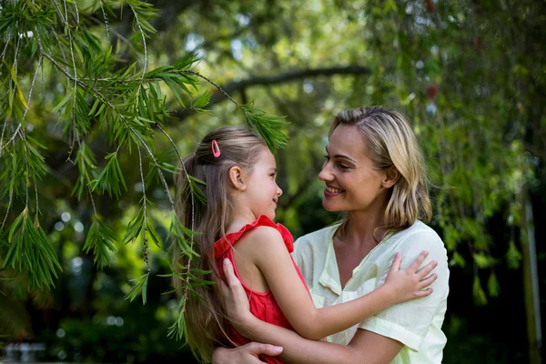 Moeder omhelst dochter in tuin — Stockfoto