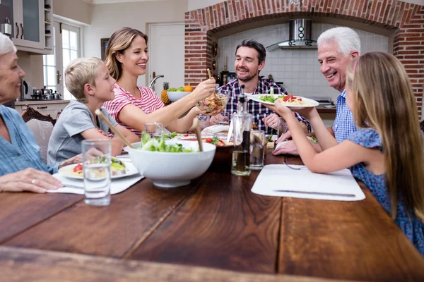 Mulher servindo comida para a família na cozinha — Fotografia de Stock