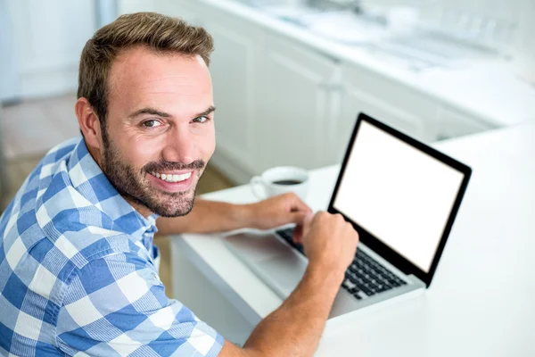 Homem usando laptop enquanto sentado à mesa — Fotografia de Stock