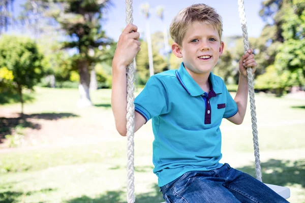 Boy sitting on swing in park — Stock Photo, Image