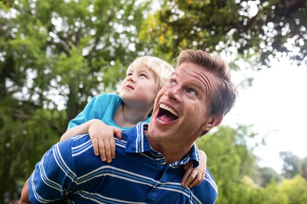 Šťastný muž piggyback dát svého syna — Stock fotografie