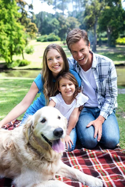 Family sitting in park with dog — Stock Photo, Image