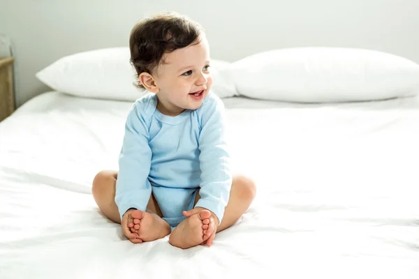 Menino sentado na cama em casa — Fotografia de Stock