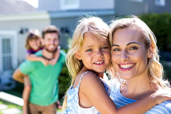 Sonrientes padres llevando hijos — Foto de Stock