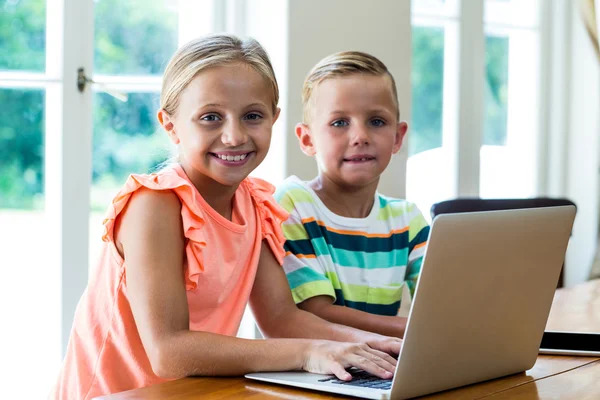 Rodzeństwo korzysta z laptopa w tabeli — Zdjęcie stockowe