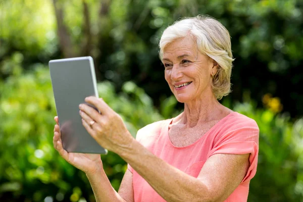 Donna anziana con tablet in cortile — Foto Stock