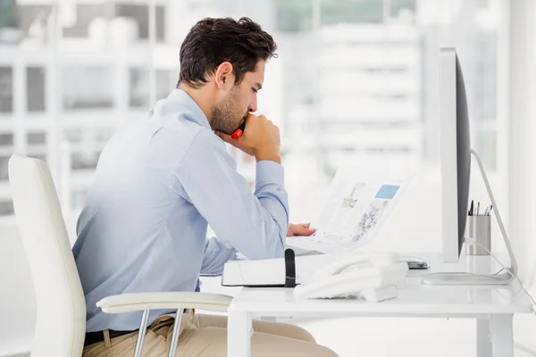 Empresario leyendo documento en su escritorio —  Fotos de Stock