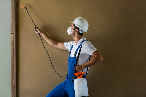 Handarbeiter sprüht Chemikalien an Wand — Stockfoto