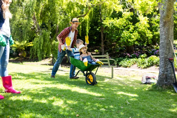 Father carrying son and daughter in wheelbarrow — Stock Photo, Image