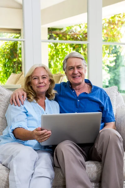 Casal sênior segurando laptop em casa — Fotografia de Stock