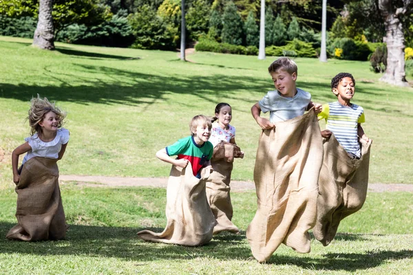 Niños haciendo una carrera de sacos en el parque — Foto de Stock