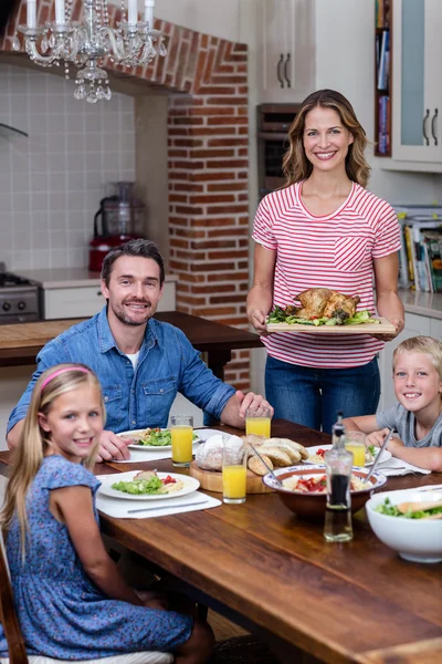 Mulher servindo comida para a família na cozinha — Fotografia de Stock