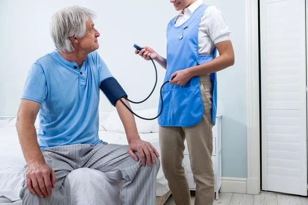 Enfermeira verificando a pressão arterial do homem — Fotografia de Stock