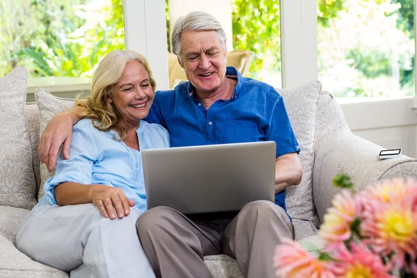 Senior couple using laptop on sofa — Stock Photo, Image