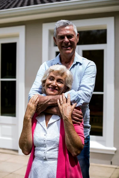 Pareja de ancianos de pie con los brazos alrededor — Foto de Stock