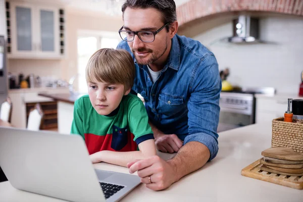 Father and son using laptop in kitchen — Stock Photo, Image