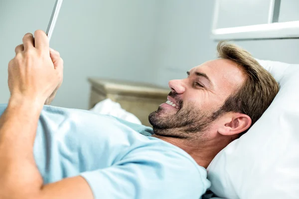 Чоловік посміхається під час використання мобільного телефону на ліжку — стокове фото