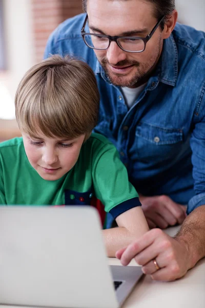 Father and son using laptop in kitchen — Stock Photo, Image