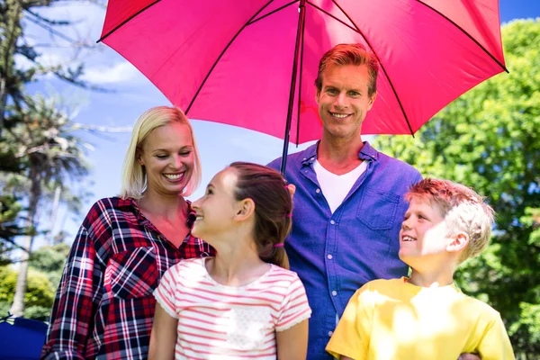 Family standing under umbrella — Stock Photo, Image