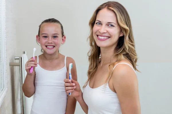 Daughter and mother holding toothbrushes — Stock Photo, Image