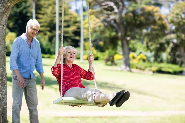 Man pushing partner on swing — Stock Photo, Image