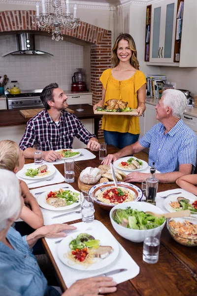 Vrouw eten serveren aan familie in keuken — Stockfoto