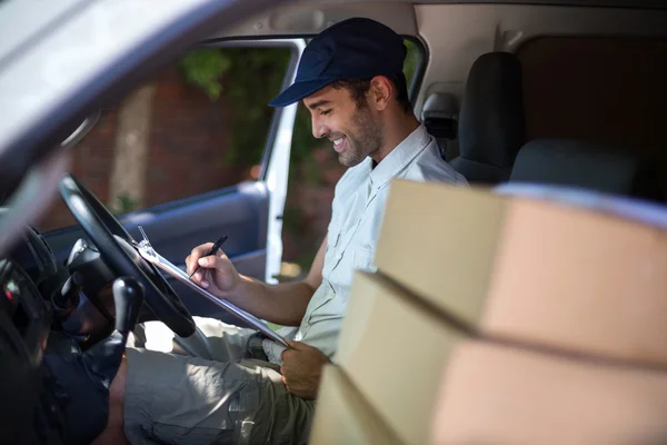 Delivery man writing in clipboard — Stock Photo, Image