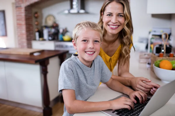 Anne ve oğul mutfakta dizüstü bilgisayar kullanarak — Stok fotoğraf