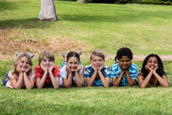 Niños felices tumbados en la hierba — Foto de Stock